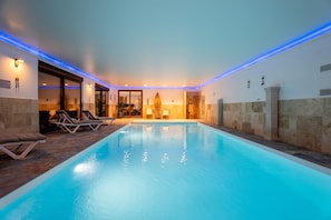 Une piscine avec des chaises longues, une porte donnant sur une pièce et une colonne.