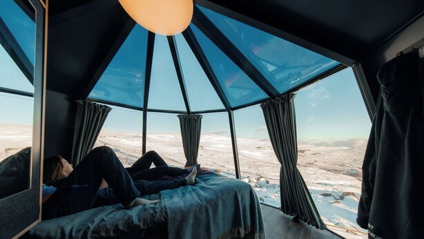 Ein Zimmer mit einem großen Fenster und Blick auf eine verschneite Landschaft.