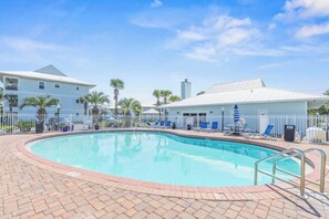 A swimming pool with lounge chairs and umbrellas, surrounded by a brick walkway and a white fence. - Renovated 30A Beach Condo • Walk to Beach • Sleeps 8 • Pools & Pickleball (Santa Rosa Beach)