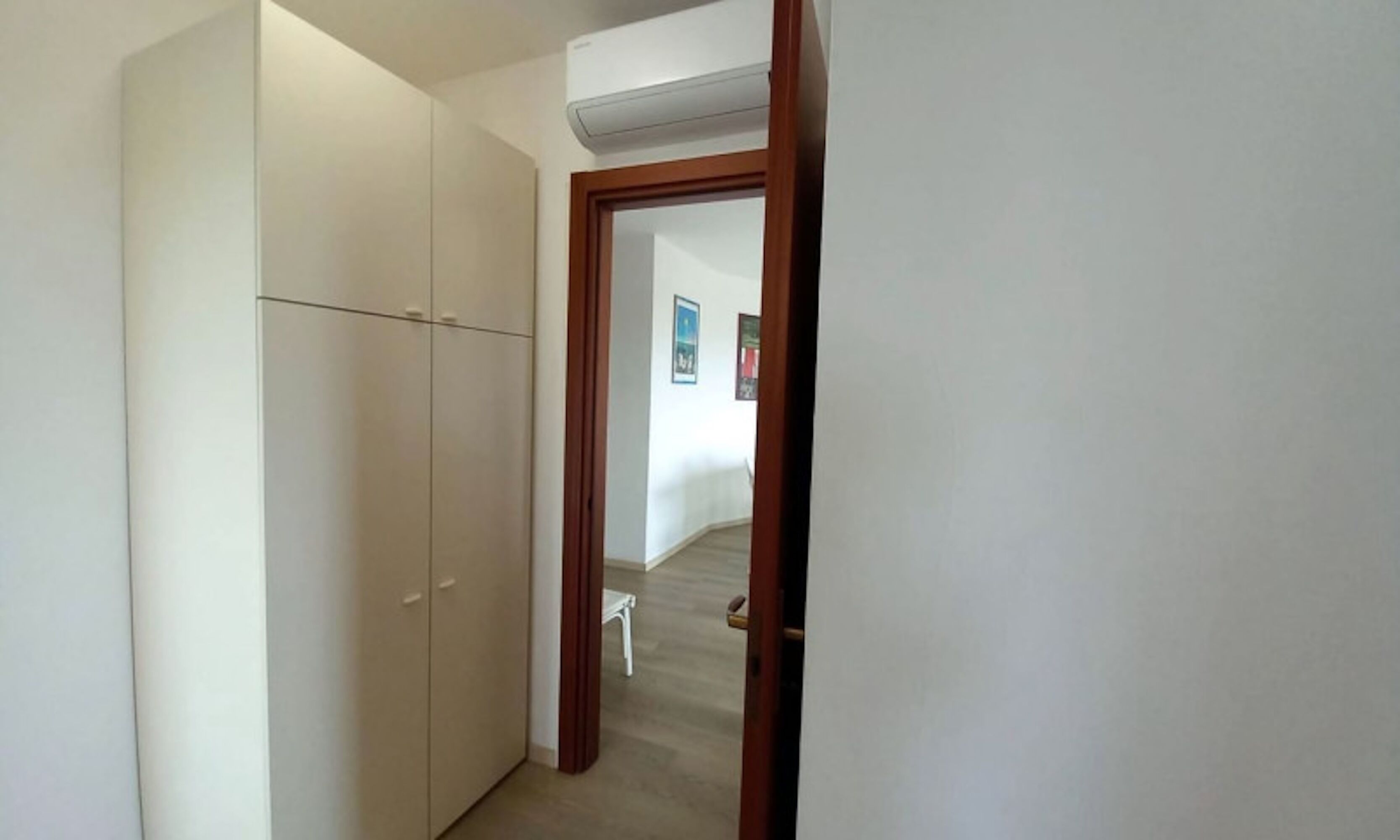 Un pasillo con un armario, una puerta que da a otra habitación y una pequeña mesa.