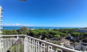 A balcony with a view of the sea, trees, and buildings. - Spacious sea View Apartment (Lignano Sabbiadoro)
