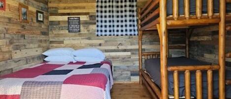 A bunk bed room with a checkered wall hanging and a wooden floor.