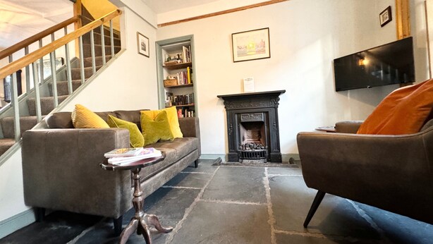 Una sala de estar con escalera, chimenea, estantería y televisor.