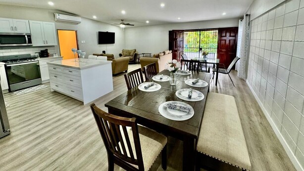 A modern kitchen with white cabinets, a built-in oven, and a dining area with a wooden table set for four. - 3-bedroom and 2 bathroom house in pleasant and safe Victoria Gardens with AC (Diego Martin Regional Corporation)