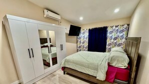 A bedroom with a bed, wardrobe, and a flat-screen TV. - 3-bedroom and 2 bathroom house in pleasant and safe Victoria Gardens with AC (Diego Martin Regional Corporation)
