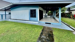 A modern house with a covered porch, a small garden, and a visible water tank in the background. - 3-bedroom and 2 bathroom house in pleasant and safe Victoria Gardens with AC (Diego Martin Regional Corporation)