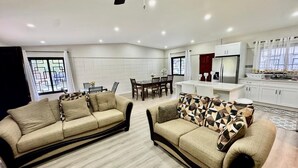 A modern living room with two sofas, a dining table, and a kitchen area. - 3-bedroom and 2 bathroom house in pleasant and safe Victoria Gardens with AC (Diego Martin Regional Corporation)