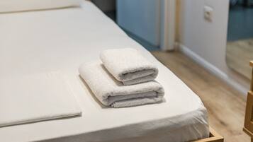 A neatly made bed with a white mattress and two folded white towels.