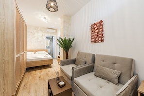 Une chambre moderne avec un lit, un canapé, une petite table et une plante en pot.