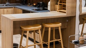 A kitchen area with wooden stools, a countertop, and a coffee machine. - NooN Apartment Sofo Duni | Beachside Studio in Dhërmi by PikHost (Dhërmi)