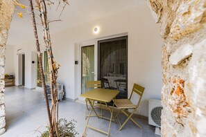 Una zona de menjador amb taula i cadires, una finestra amb cortines i una paret de pedra.