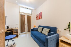 A modern living room with a blue sofa, a coffee station, and a sliding glass door. - NooN Properties | 3 by PikHost (Dhërmi)