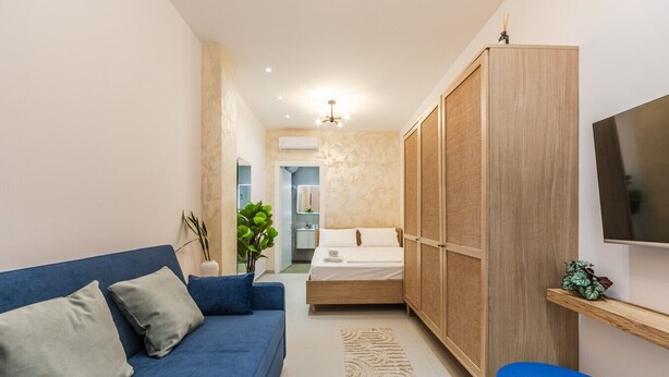 Ein modernes Schlafzimmer mit einem blauen Sofa, einem Bett, einem Kleiderschrank und einem Fernseher.