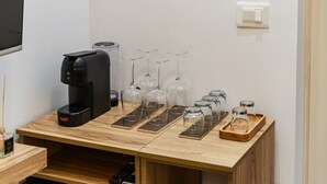 Eine Kaffeemaschine, Weingläser und Gläser auf einem Holztisch in einem Raum.