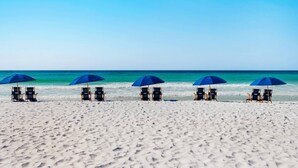 Una playa con cinco filas de sillas y sombrillas, dispuestas en línea.