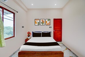 A bedroom with a bed, a window, a red door, and three framed artworks on the wall. - Hotel O Vijay Shree Marriage Hall (Gopalganj)