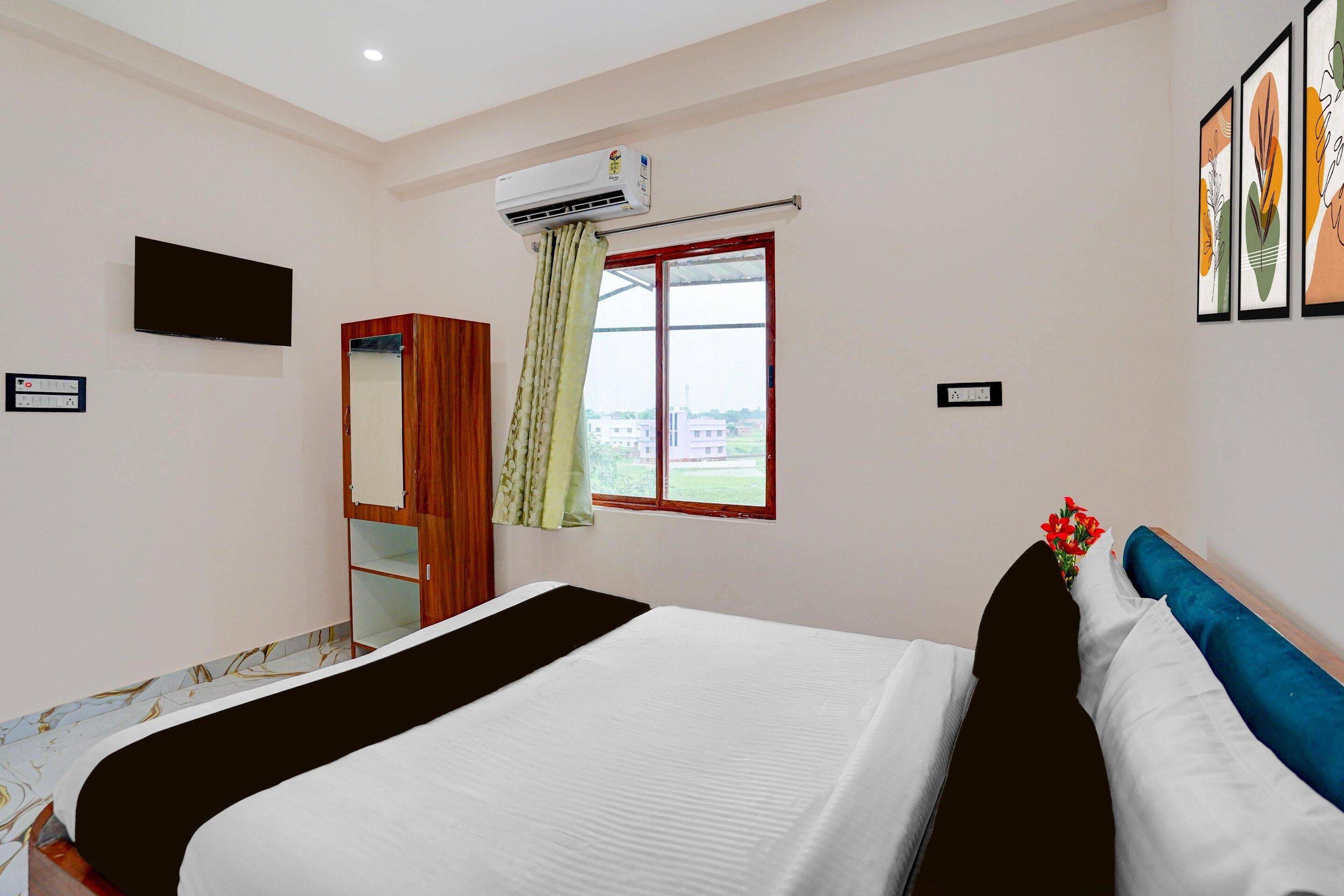 Hotelkamer met een bed, een kledingkast, een televisie, een airconditioningapparaat, een raam met gordijnen en lijstwerken aan de muur.
