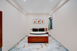 A bedroom with a bed, a nightstand, a wall-mounted air conditioner, and framed artwork on the wall. - Hotel O Vijay Shree Marriage Hall (Gopalganj)