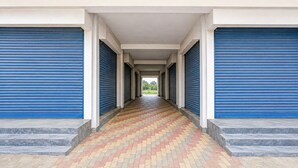 A corridor with blue shutters, a tiled floor, and a series of steps leading to an open area.