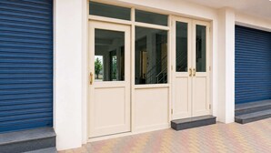 Une entrée d’immeuble avec un ensemble de portes doubles, un escalier et une porte de garage bleue à volets.