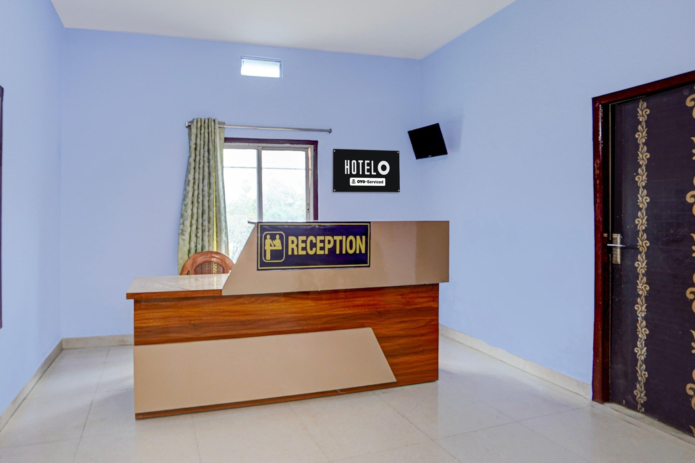 A hotel reception desk with a sign indicating it is an OYO-Serviced hotel.