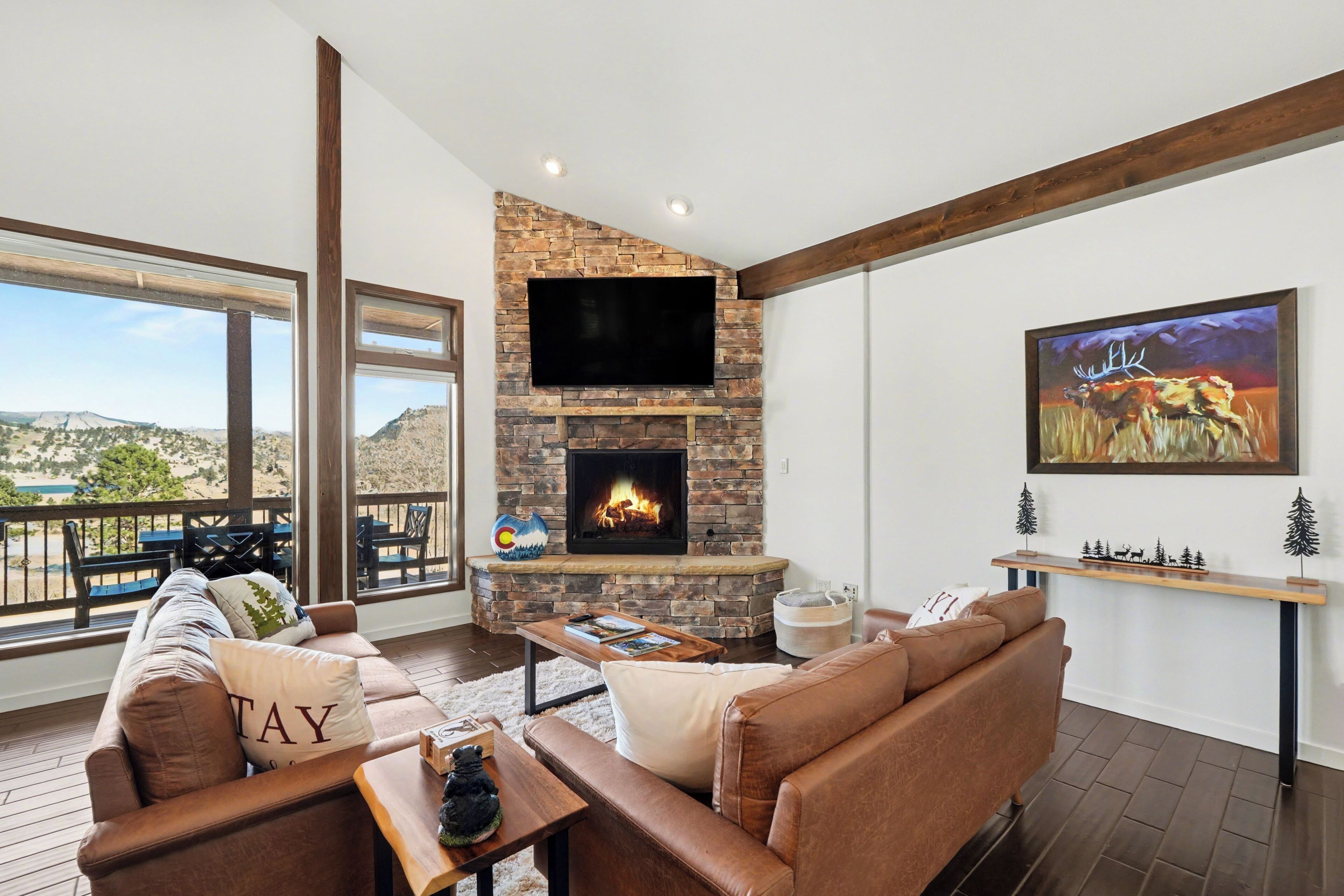 A living room with a stone fireplace, a flat-screen TV, a sofa, and a painting.