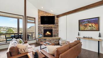 A living room with a stone fireplace, a flat-screen TV, a sofa, and a painting.