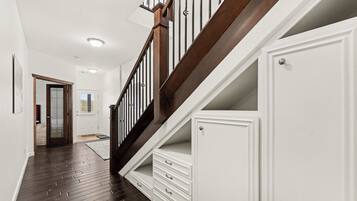A staircase with wooden railings and white walls, leading to a door with a glass panel.