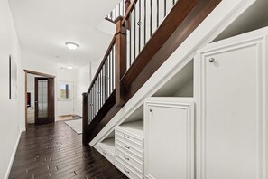 Eine Treppe mit hölzernen Geländern und weißen Wänden, die zu einer Tür mit Fensterteil führt.