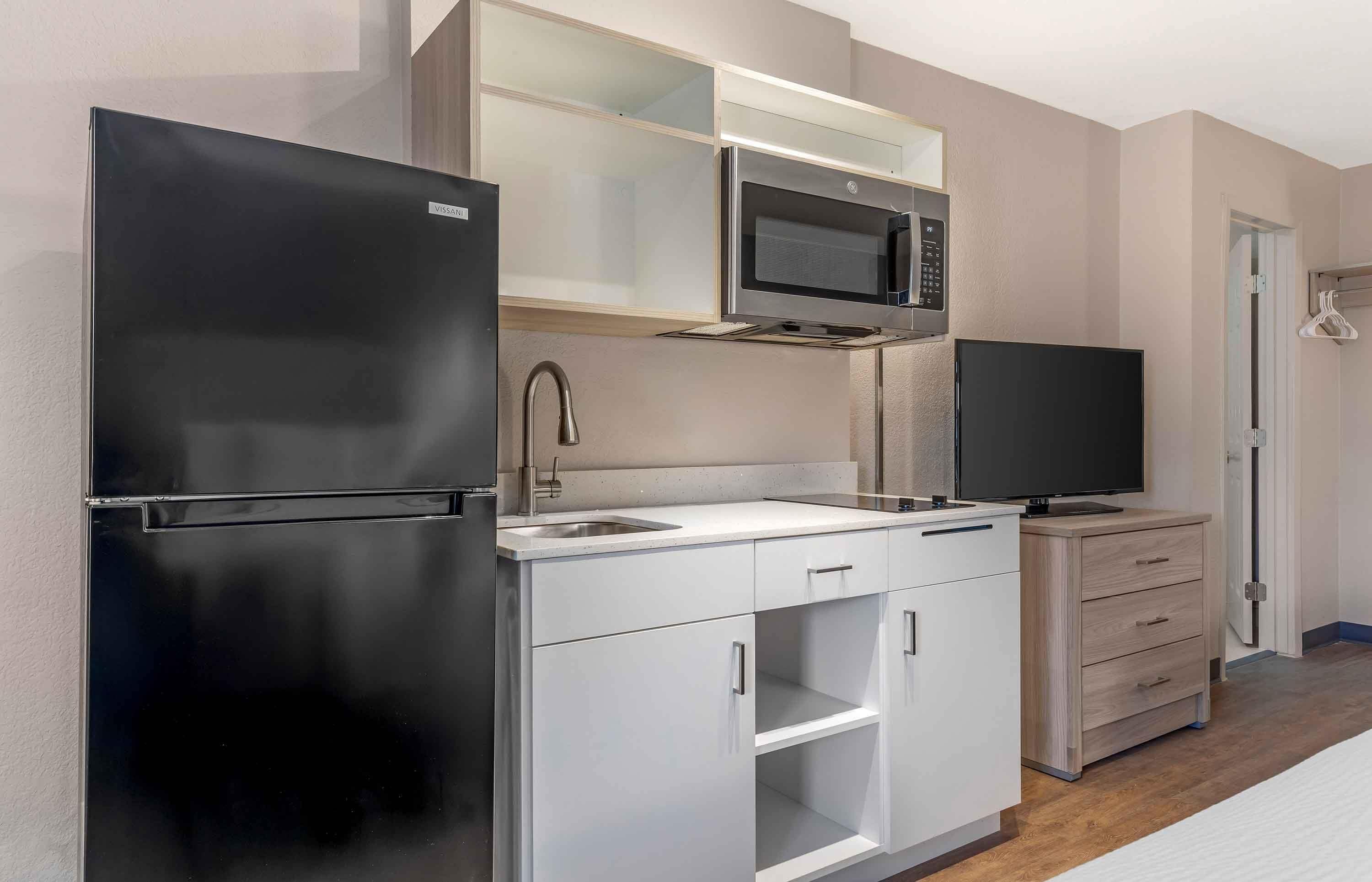 Cocina compacta equipada con refrigerador, microondas, pileta y televisión.