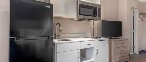 Cocina compacta equipada con refrigerador, microondas, pileta y televisión.