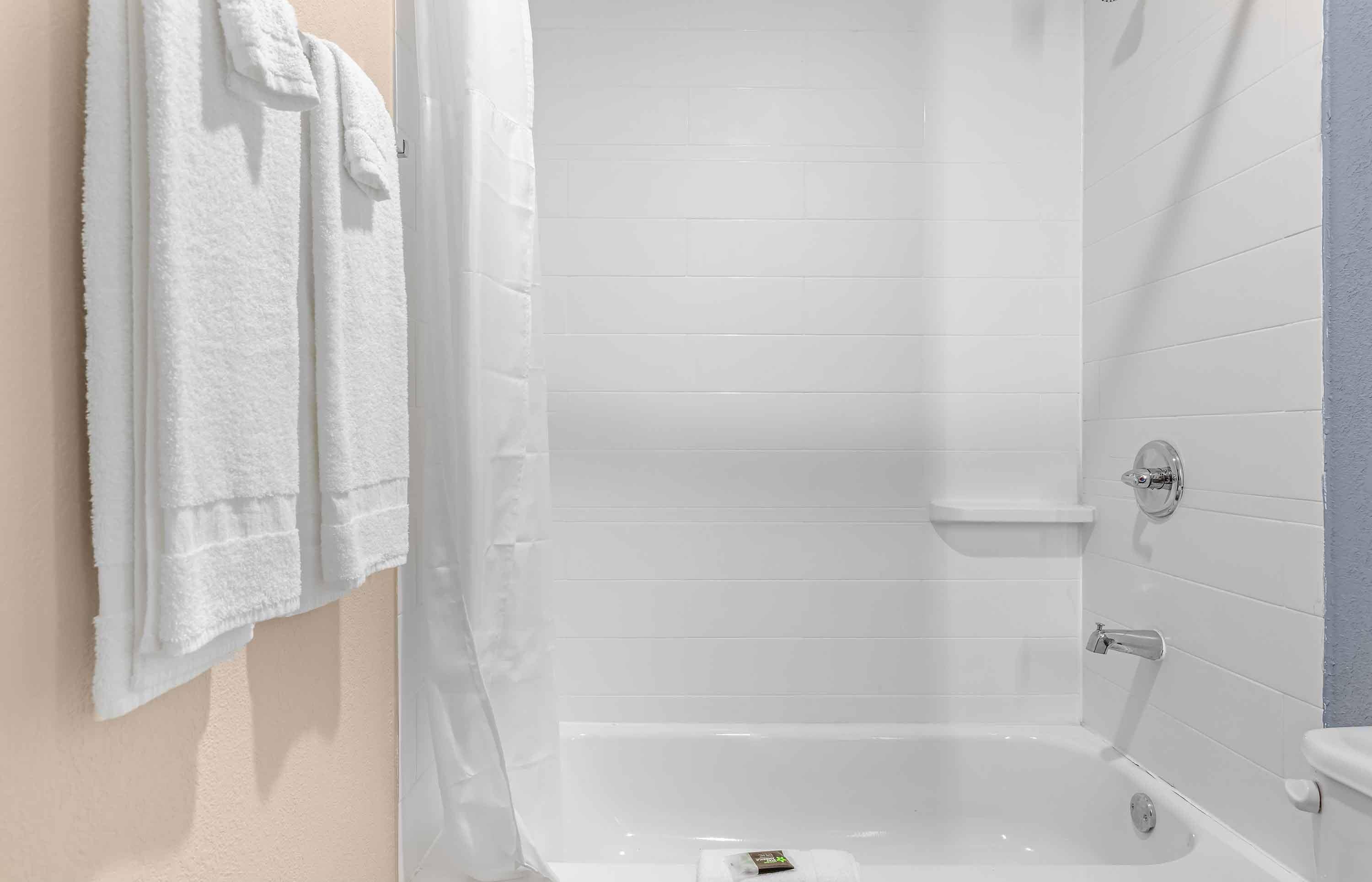 Un baño con bañera, ducha e inodoro. Hay toallas colgadas en la pared.
