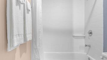 Un baño con bañera, ducha e inodoro. Hay toallas colgadas en la pared.