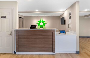 A reception desk with a modern design, a digital screen, and a green decorative element on the wall.