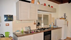 A kitchen with wooden cabinets, a gas stove, a sink, and a refrigerator. - Marta's Studio in Formia (Formia)