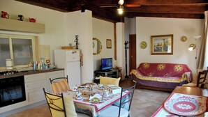 A cozy kitchen with a dining area, a sofa, and a television. - Marta's Studio in Formia (Formia)