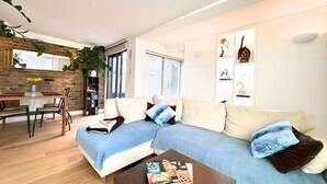 Ein modernes Wohnzimmer mit Sofa, Couchtisch und einem Essbereich mit Tisch und Stühlen.