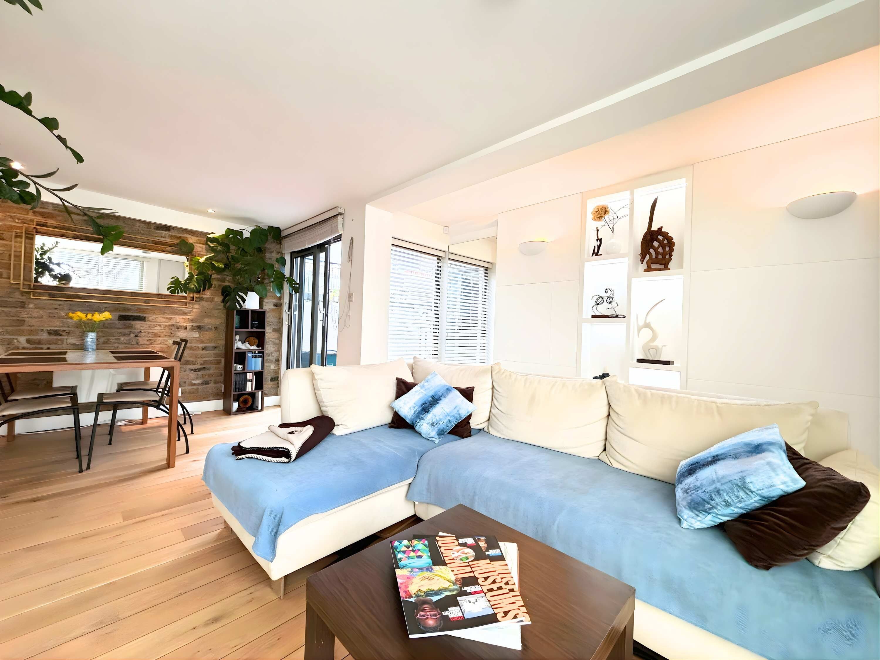 A modern living room with a sofa, coffee table, and a dining area with a table and chairs.