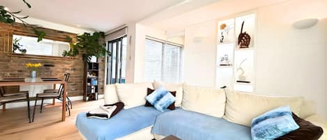 A modern living room with a sofa, coffee table, and a dining area with a table and chairs.