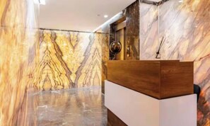 A reception area with marble walls and a wooden reception desk. - New and modern 3 bedrooms, 2 bedrooms in Gueliz (Marrakesh)