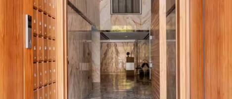 A hallway with wooden lockers on one side and a marble floor.