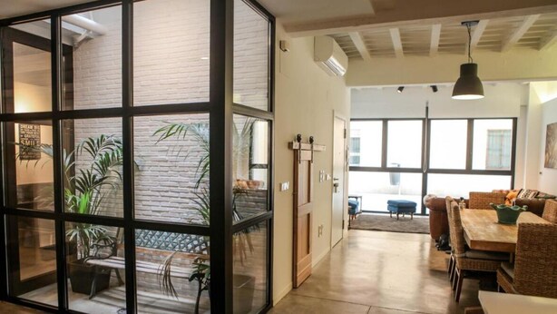 Ein modernes Interieur mit Glastrennwand, Rattanmöbeln und Blick in einen Essbereich.