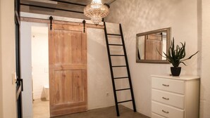 Ein Zimmer mit einer Holztür, einer weißen Kommode mit Schubladen, einer Topfpflanze, einem Spiegel und einer Kristallleuchter.