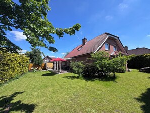 A house with a red-tiled roof, a brick exterior, and a well-maintained lawn.