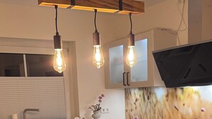 Een moderne keuken met een houten eiland, hanglampen en een flatscreen televisie boven het eiland.