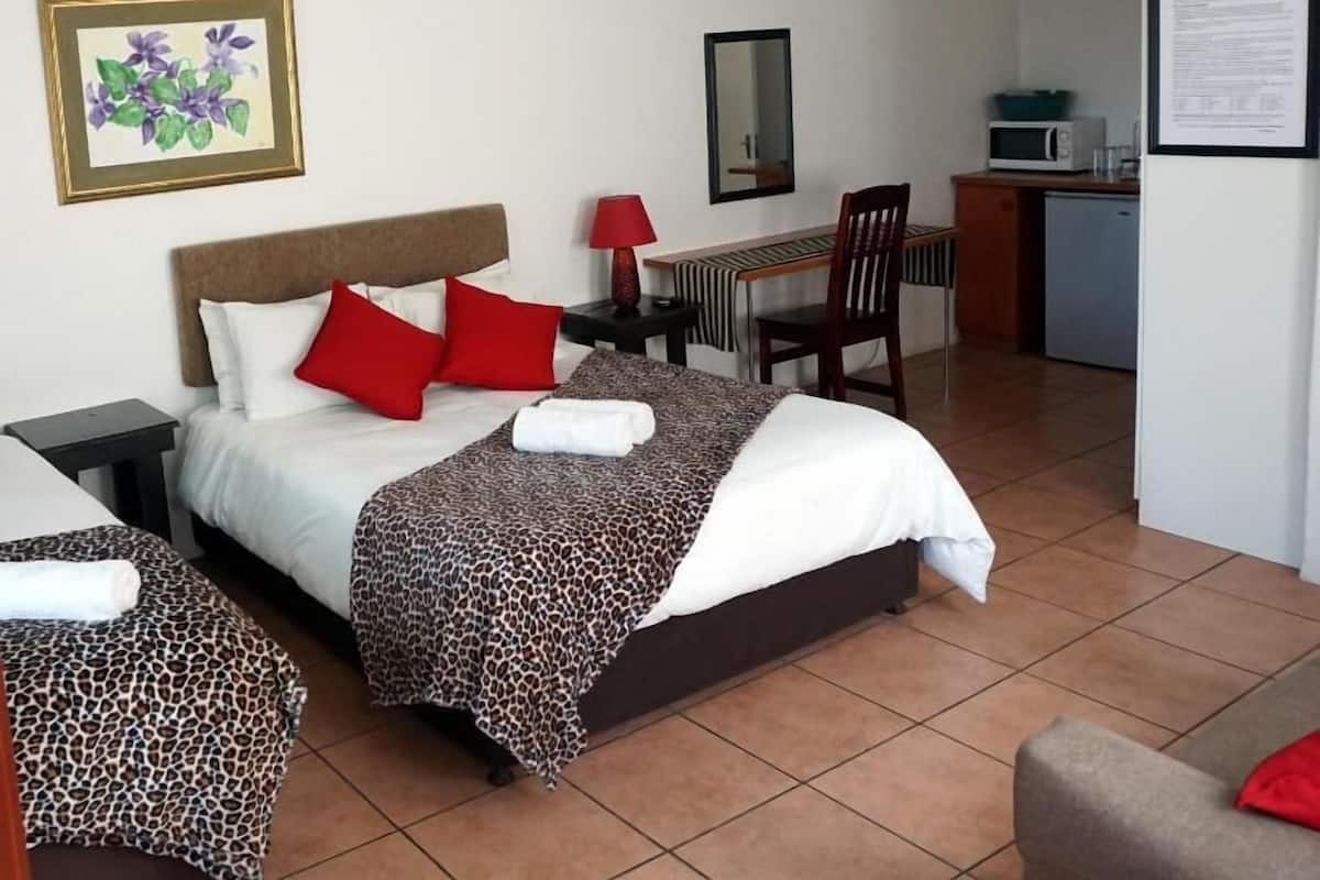 Habitación de hotel con dos camas, un escritorio, una silla, un microondas y un refrigerador.