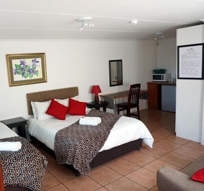 Habitación de hotel con dos camas, un escritorio, una silla, un microondas y un refrigerador.