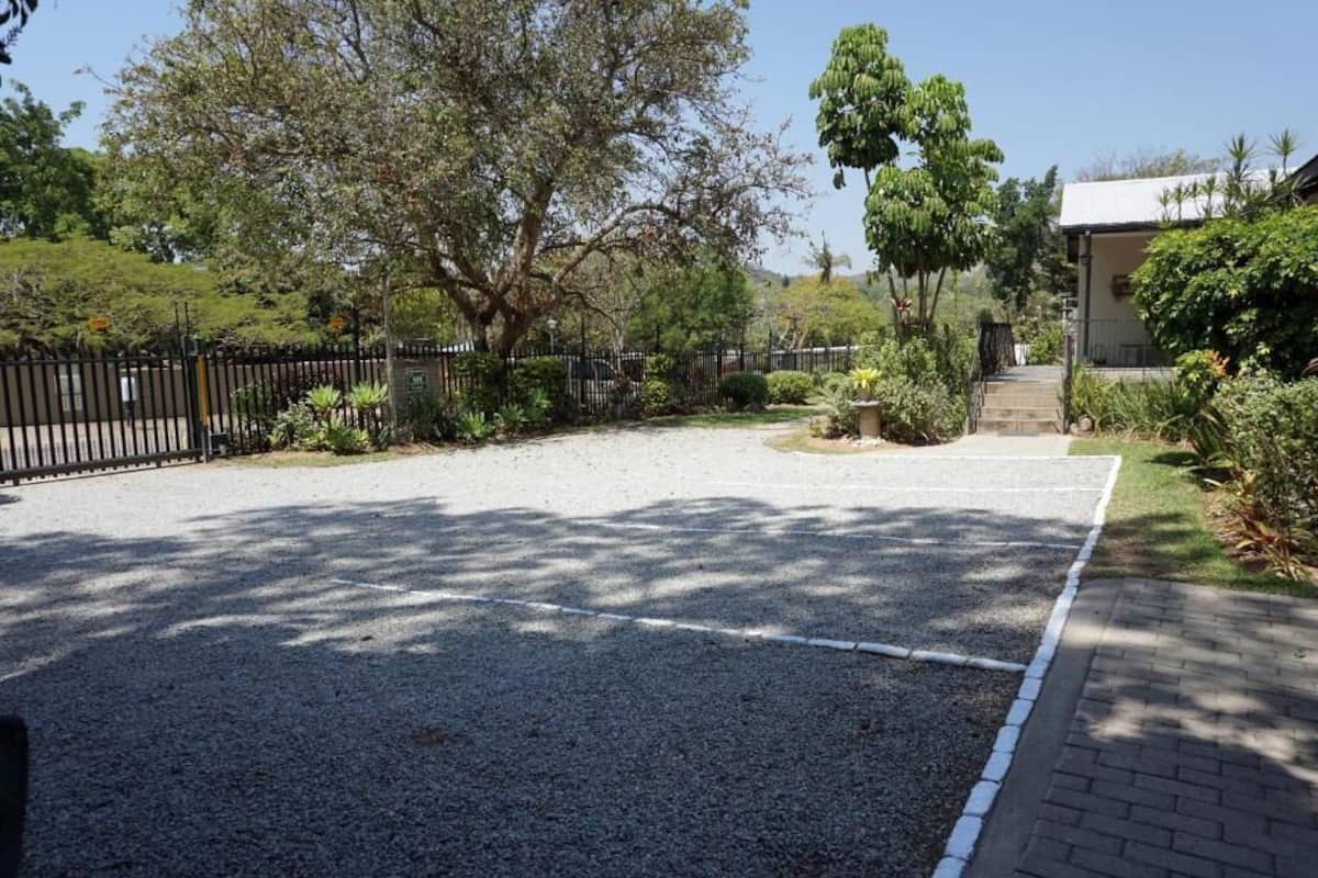 Un camino de grava que conduce a un edificio con un sendero de ladrillo y una valla de metal negro.
