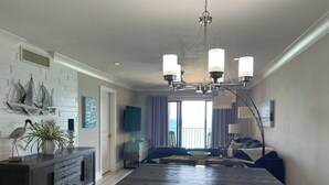 Ein moderner Essbereich mit einem Holztisch und Stühlen, einer Chandelierleuchtre und Blick auf den Ozean durch große Fenster.