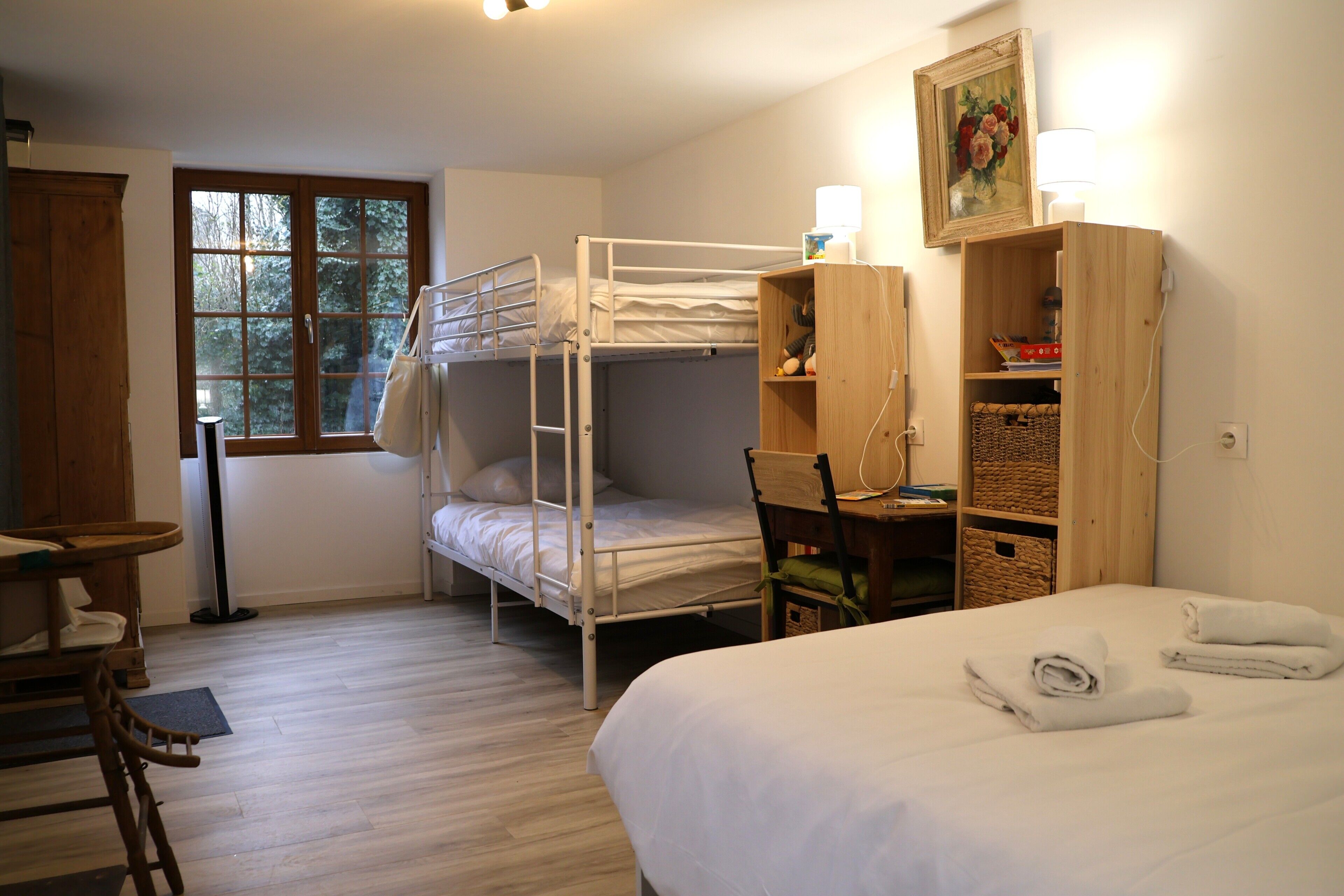 Una habitación con literas, un escritorio, una silla, una lámpara y una estantería.